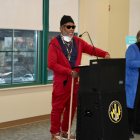 A middle-aged man in a red onesie standing at a Baltimore City podium